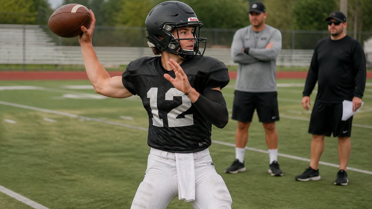 High school quarterback in full uniform executing a throwing motion during organized practice, with coaches observing in background, natural field lighting